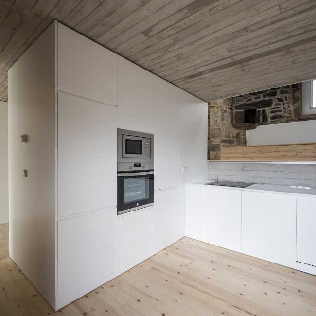 Interior de piedra y cemento con cocina blanca