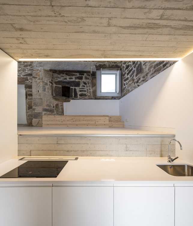 Interior de piedra y cemento con cocina blanca