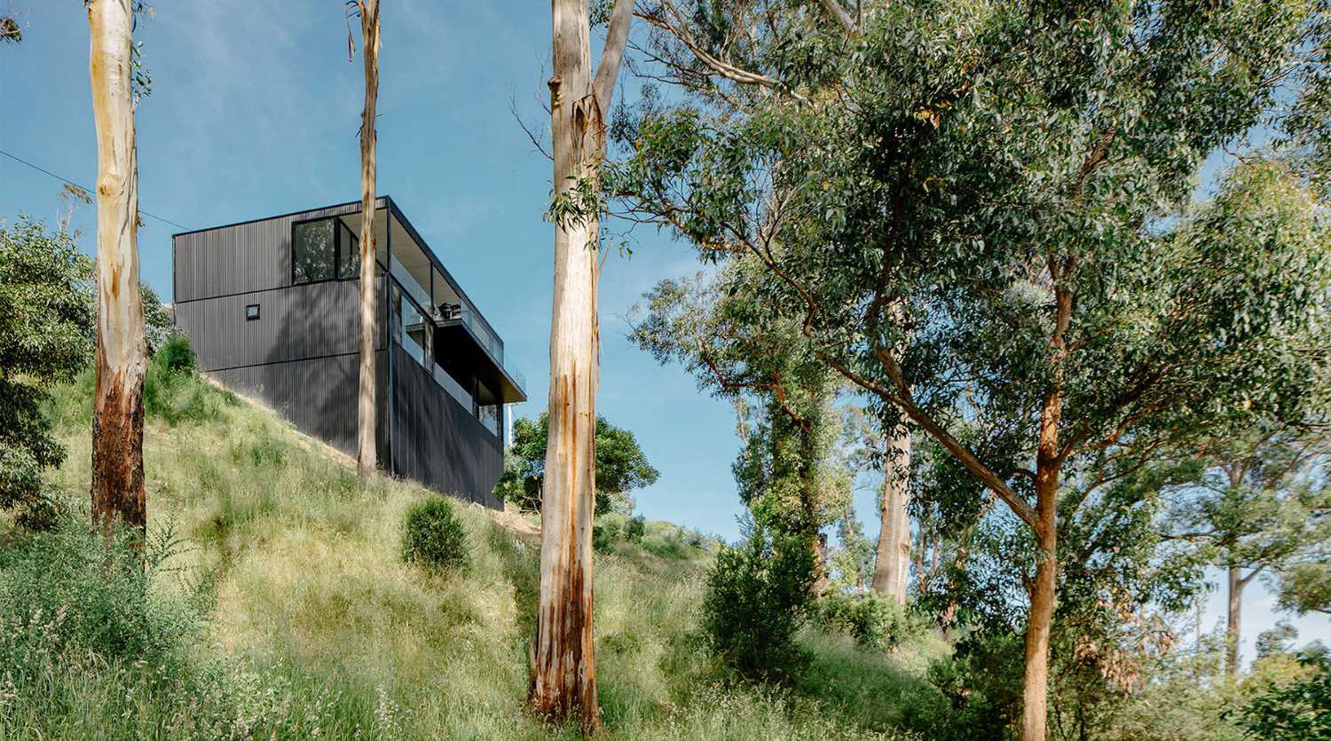 Maison perchée sur une colline. Extérieur sombre et intérieur avec vue sur l'océan