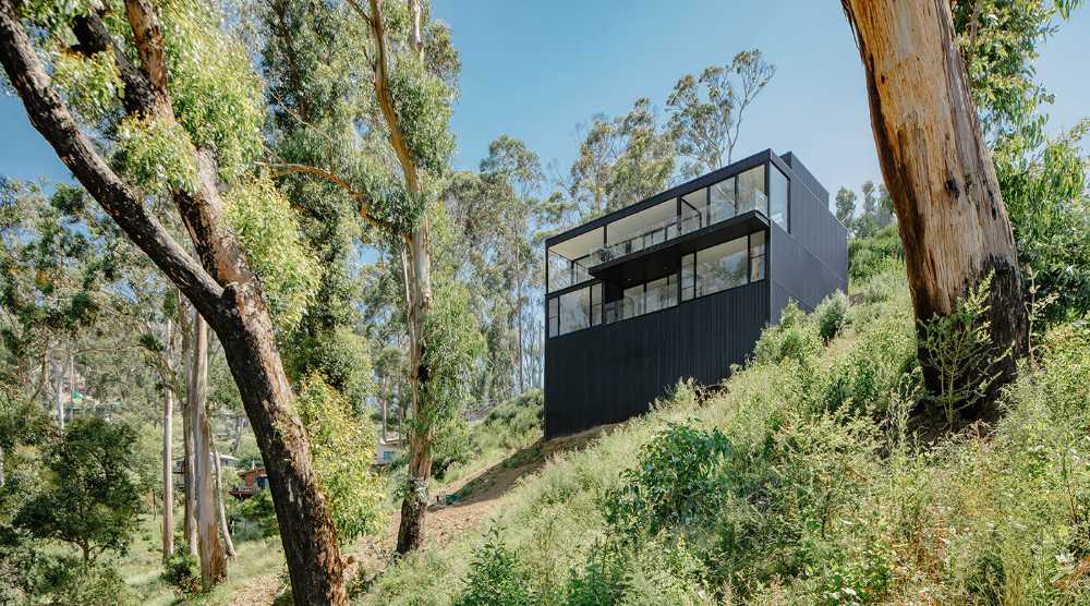 Maison perchée sur une colline. Extérieur sombre et intérieur avec vue sur l'océan