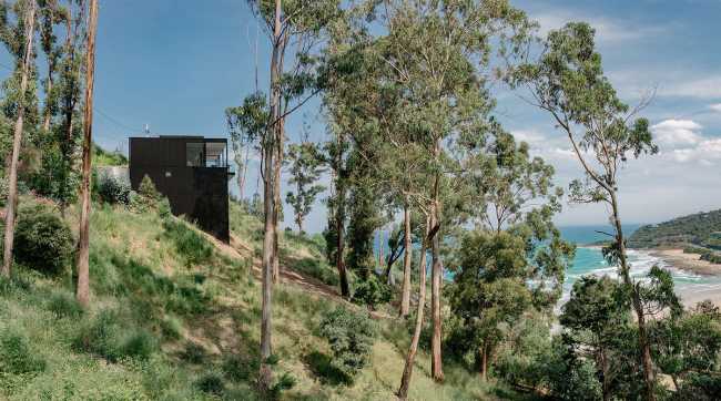 Maison perchée sur une colline. Extérieur sombre et intérieur avec vue sur l'océan