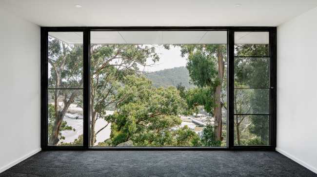 Maison perchée sur une colline. Extérieur sombre et intérieur avec vue sur l'océan