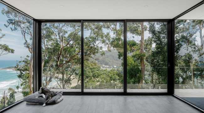 Maison perchée sur une colline. Extérieur sombre et intérieur avec vue sur l'océan