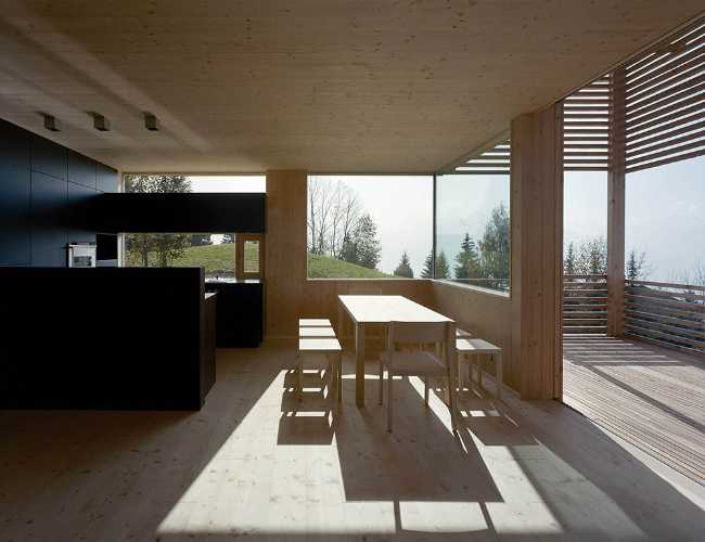 Living room of a wooden cabin with view of the Alpine landscape