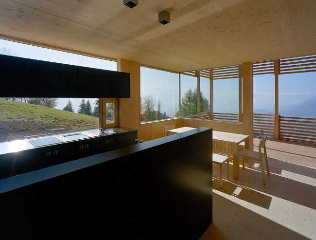 Living room of a wooden cabin with view of the Alpine landscape