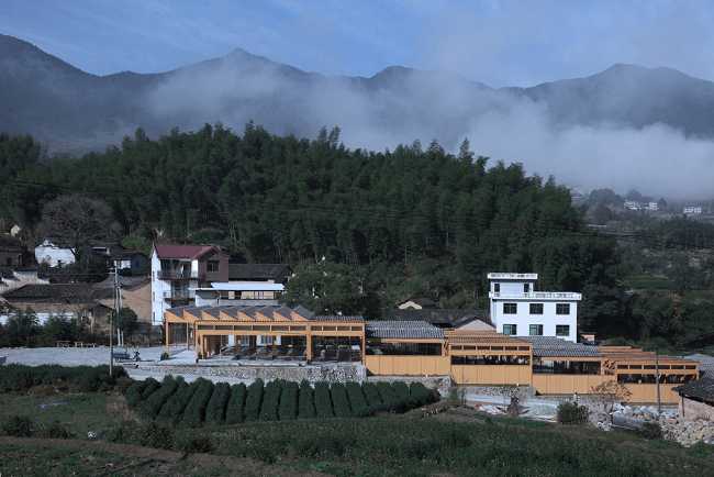 wooden factory nestled along a slope with mountains background
