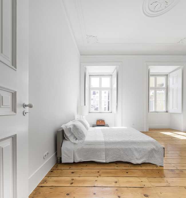 Camera da letto con pareti bianche e parquet