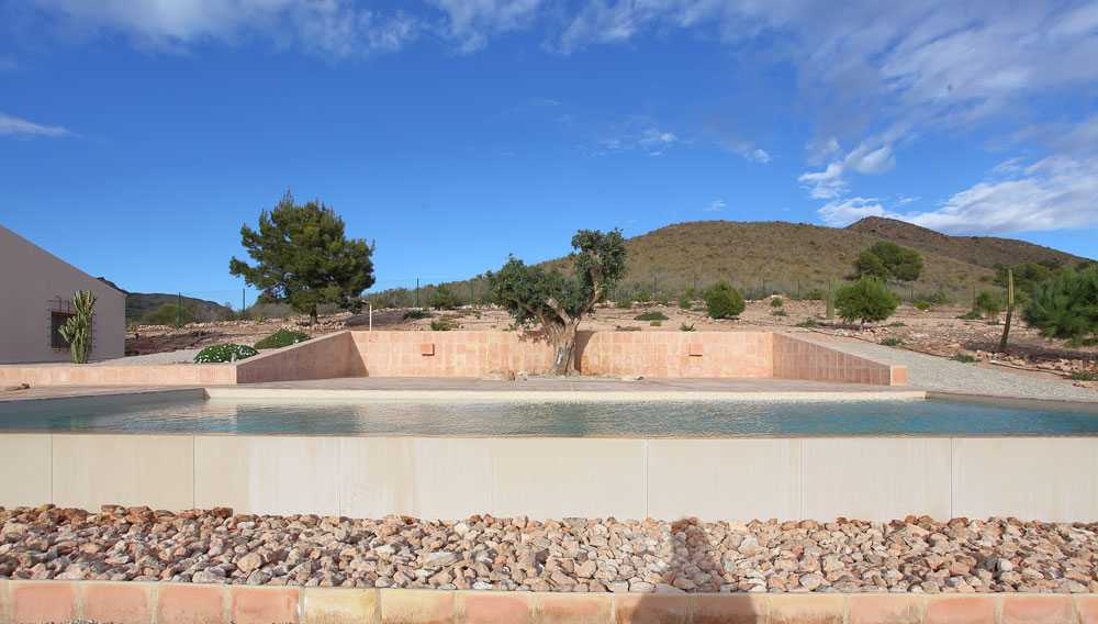 Casa mediterránea ubicada entre campos arados y piedras. Hábitat ecológico en España