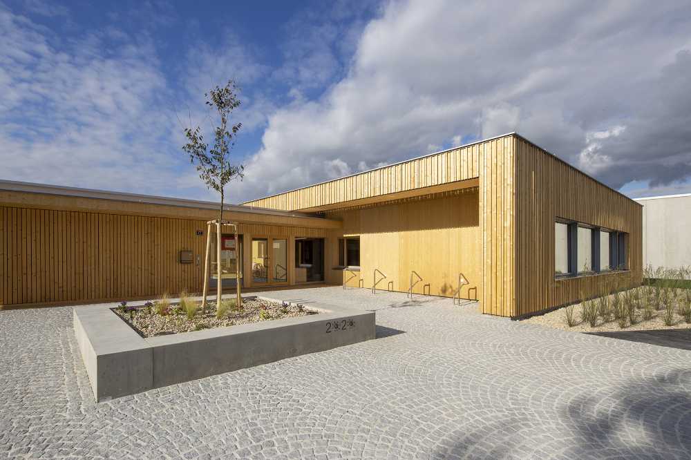 Jardín de infancia de madera maciza. Edificio de una sola planta en un ambiente heterogéneo